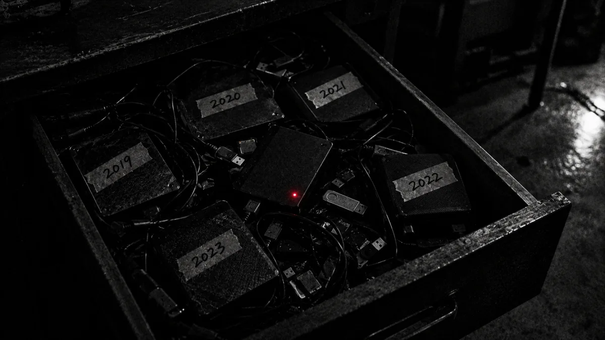 ① A drawer of drives labeled by year — one unlabeled drive with a red light
